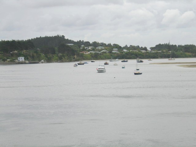 Houhora Harbour. Moored boats near wharf overlooked by residents. Far North, North Island, New Zealand